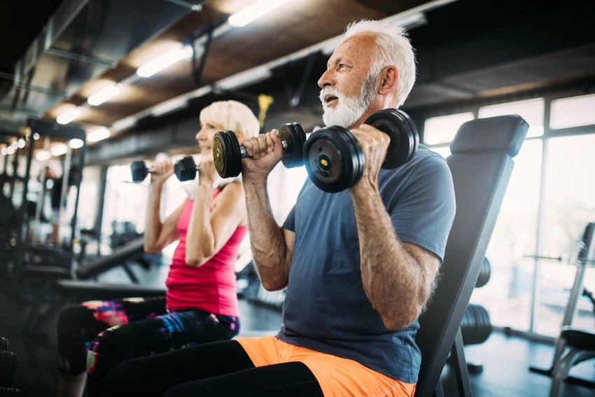 Zwei ältere Menschen traineren zusammen im Fitnessstudio dank Health Club.